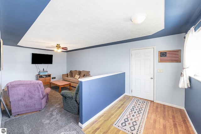 living area with ceiling fan, baseboards, and wood finished floors