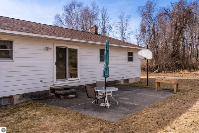 back of house featuring a patio, roof with shingles, and a chimney