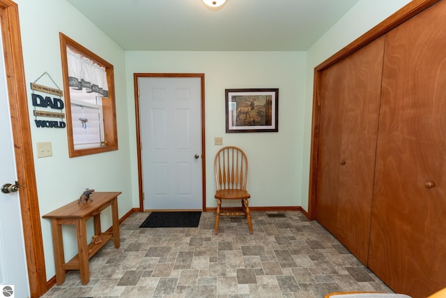 entrance foyer featuring stone finish floor and baseboards