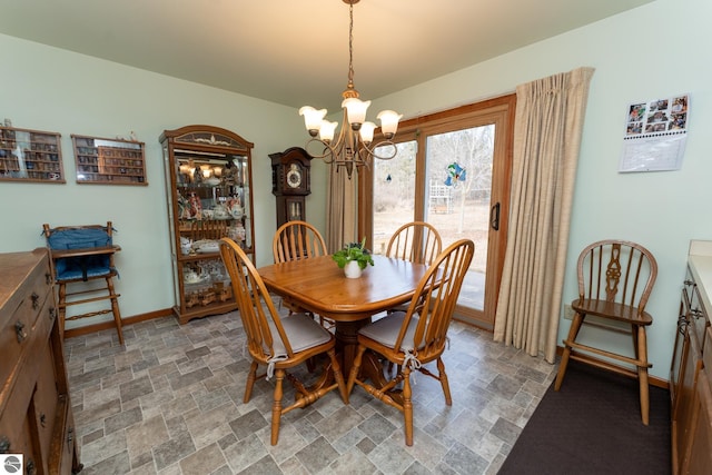 dining space with a chandelier, stone finish floor, and baseboards