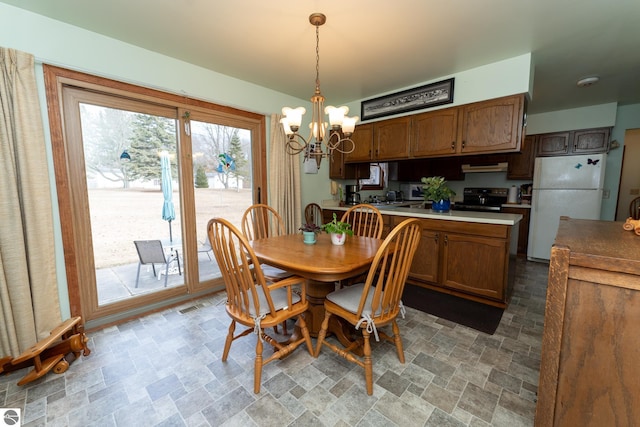 dining room featuring stone finish flooring and an inviting chandelier