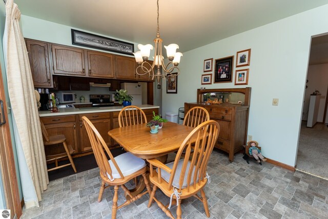 dining room featuring a notable chandelier, baseboards, and stone finish flooring