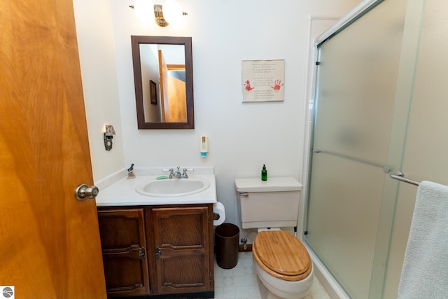 bathroom with toilet, vanity, and a shower with shower door