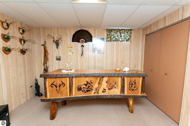 interior space with a paneled ceiling and wooden walls