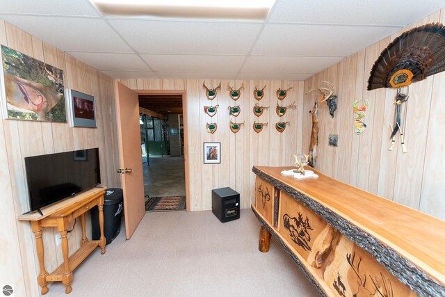 interior space featuring wooden walls, a paneled ceiling, and light carpet