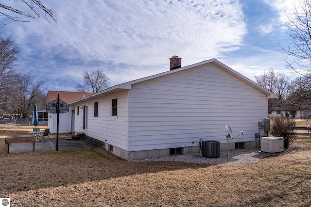 view of side of home with a patio, central AC unit, and a chimney