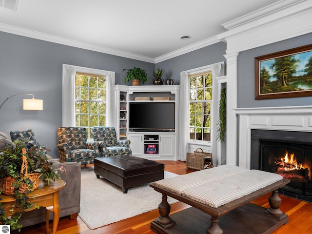 living room with crown molding, wood finished floors, and a lit fireplace