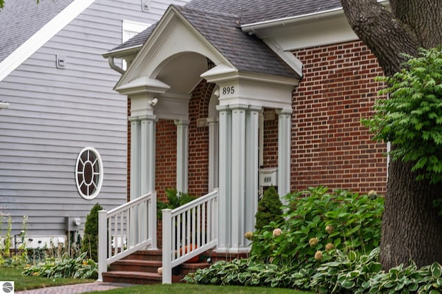 entrance to property with brick siding and roof with shingles