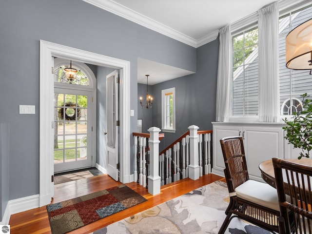 foyer entrance with baseboards, an inviting chandelier, wood finished floors, and crown molding