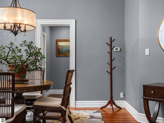 dining area with a chandelier, baseboards, and wood finished floors