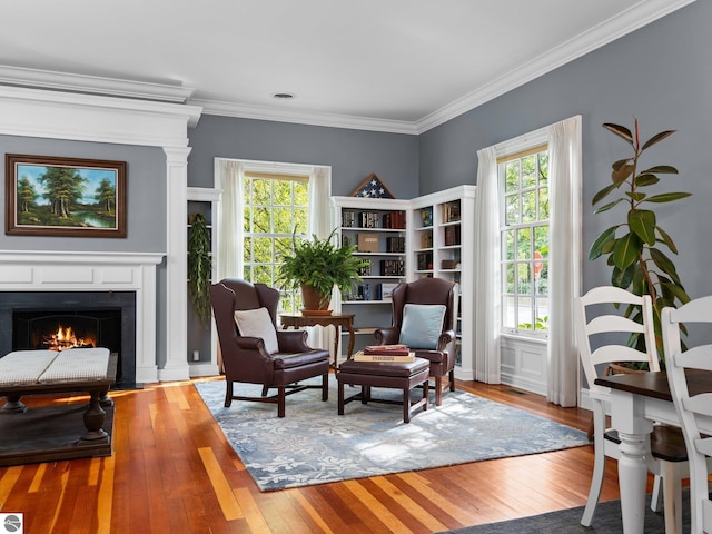 sitting room with a fireplace with flush hearth, hardwood / wood-style floors, and ornamental molding