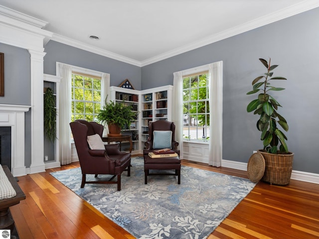 sitting room featuring hardwood / wood-style floors, a fireplace, baseboards, and ornamental molding