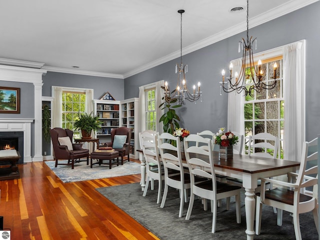 dining room with visible vents, a warm lit fireplace, wood finished floors, and ornamental molding