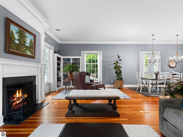 living area with plenty of natural light, wood finished floors, a fireplace with flush hearth, and ornamental molding