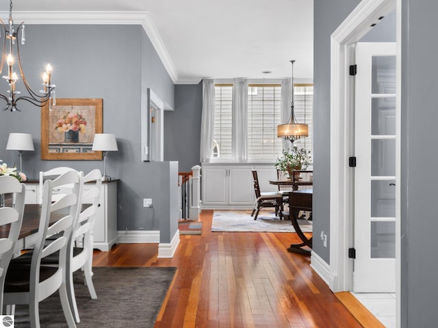 interior space featuring baseboards, an inviting chandelier, crown molding, and hardwood / wood-style flooring