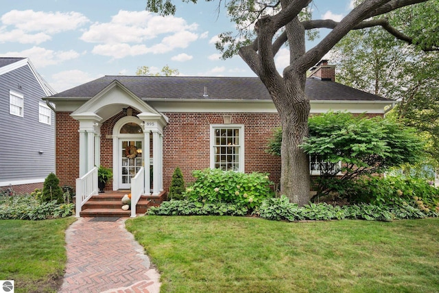 view of front facade with a front lawn, brick siding, and a chimney