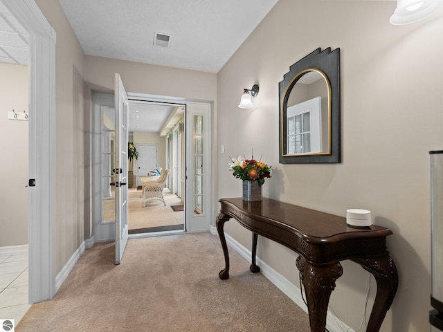 corridor featuring visible vents, light colored carpet, french doors, and baseboards