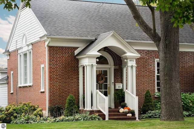 view of front facade with brick siding and roof with shingles