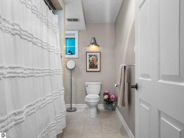 bathroom featuring tile patterned floors, visible vents, toilet, a textured ceiling, and baseboards