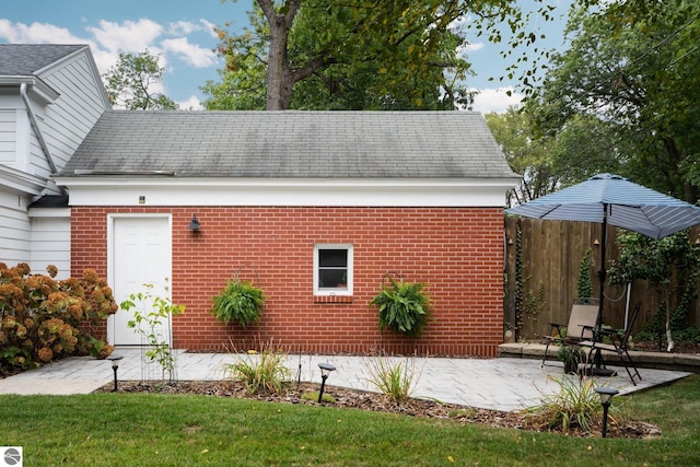 view of property exterior with a patio area, fence, and brick siding