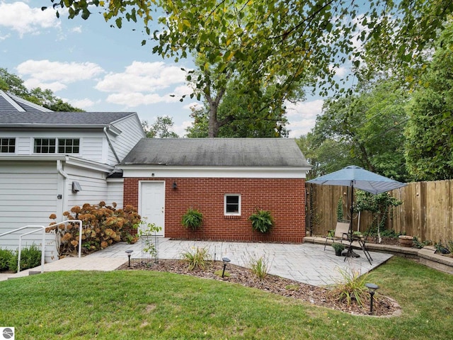 view of front facade with a patio area, brick siding, a front lawn, and fence