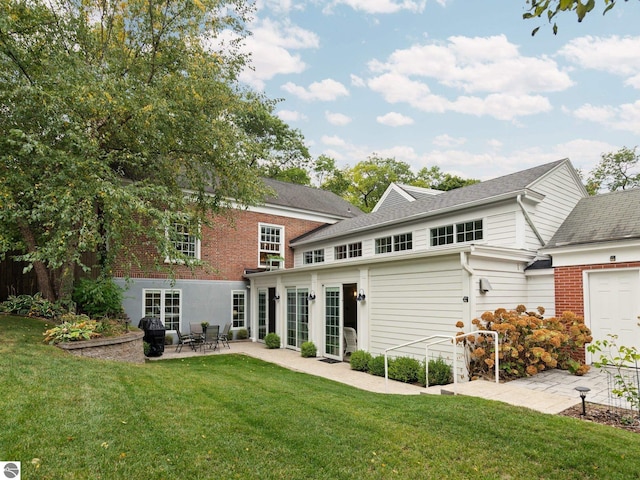 back of house featuring brick siding, a lawn, french doors, and a patio