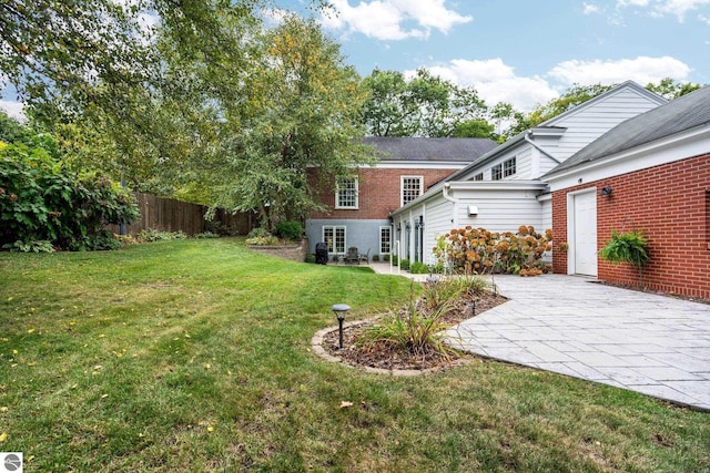 view of yard with driveway, a patio, and fence