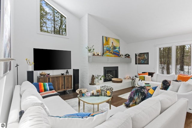 living area with a fireplace, high vaulted ceiling, and wood finished floors