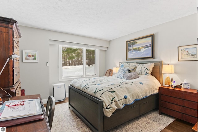 bedroom with baseboards, a textured ceiling, and wood finished floors