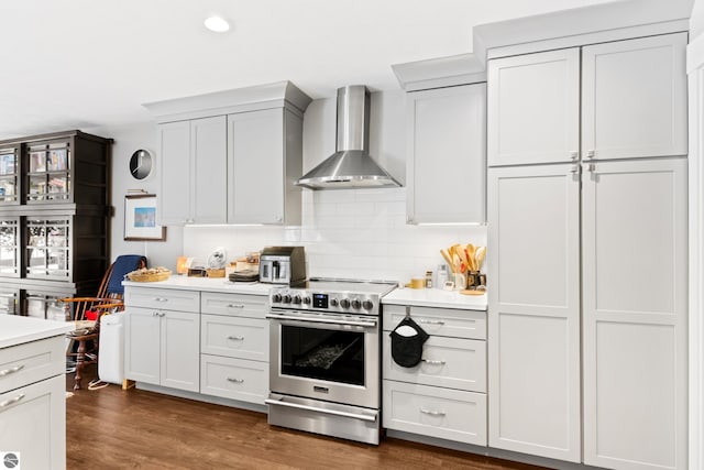 kitchen with wall chimney range hood, dark wood-style floors, stainless steel electric range, light countertops, and decorative backsplash