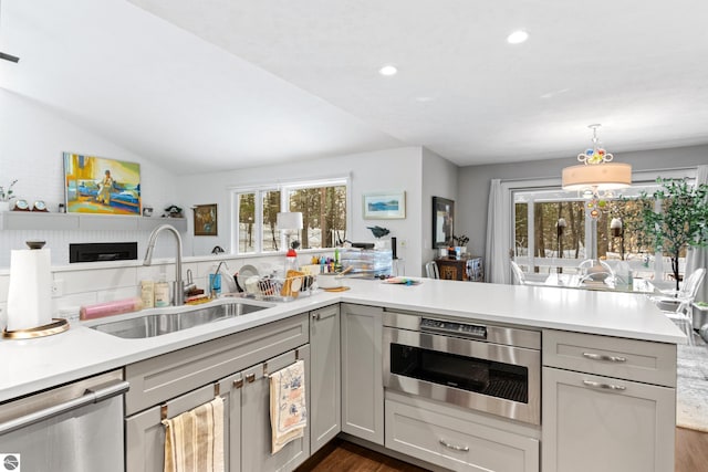 kitchen featuring dishwasher, light countertops, gray cabinetry, and a sink