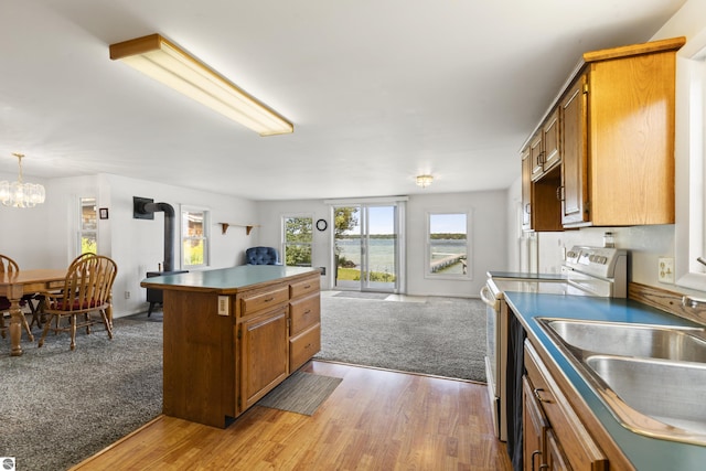 kitchen with white electric range oven, brown cabinetry, open floor plan, and a sink