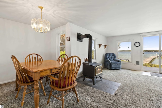 carpeted dining room with an inviting chandelier, a wood stove, and baseboards