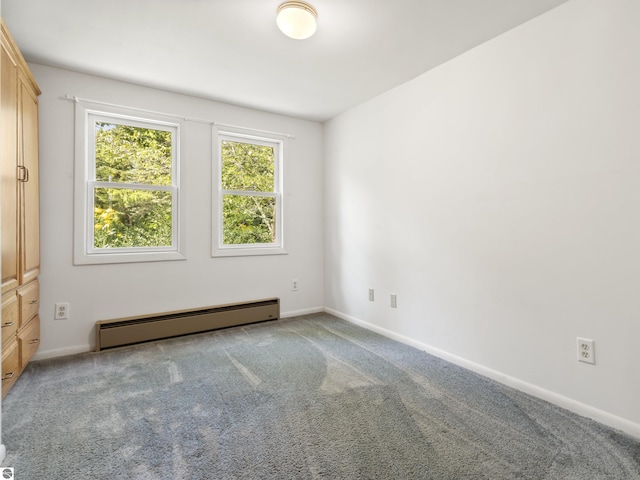 carpeted empty room with a baseboard heating unit and baseboards