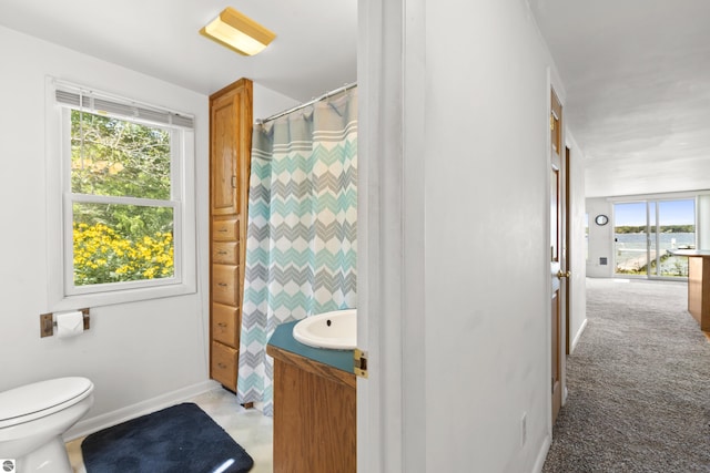 bathroom featuring vanity, a shower with shower curtain, toilet, and baseboards