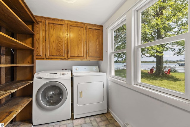 laundry area featuring cabinet space, washer and dryer, brick floor, and baseboards