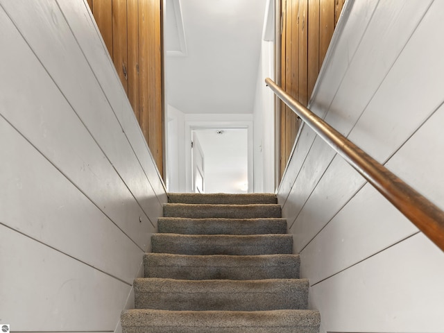 stairs featuring wood walls