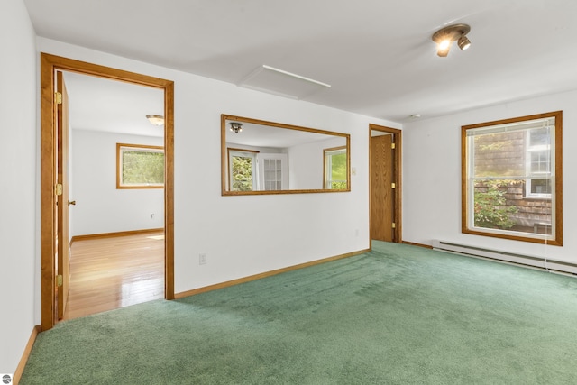 carpeted spare room featuring baseboard heating, attic access, and baseboards