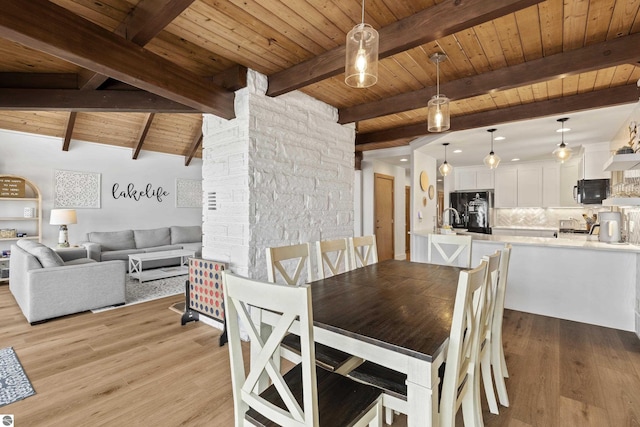 dining area with light wood finished floors, vaulted ceiling with beams, and wood ceiling