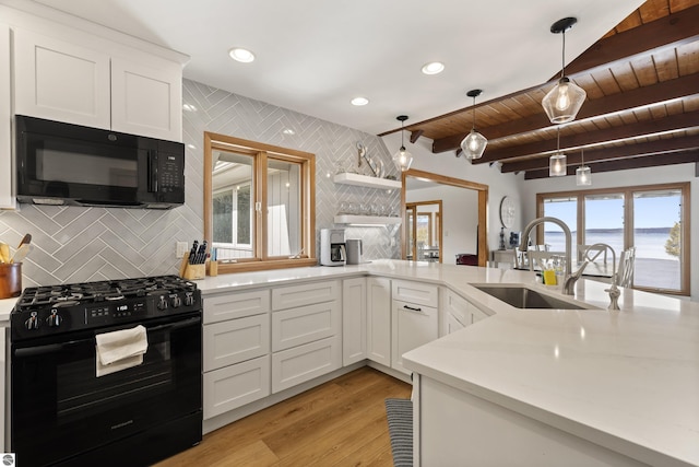 kitchen featuring black appliances, a sink, tasteful backsplash, light wood-style floors, and light countertops