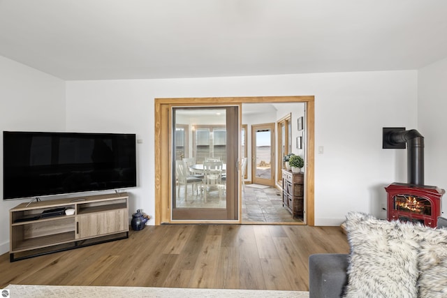 living area featuring a wood stove, wood finished floors, and baseboards