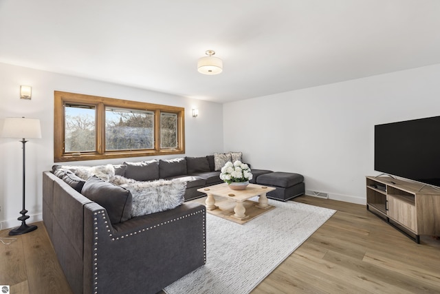 living area with visible vents, light wood-style floors, and baseboards