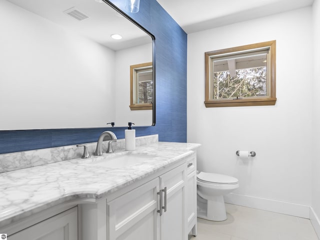 bathroom with vanity, baseboards, visible vents, tile patterned flooring, and toilet