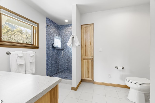 bathroom with tile patterned floors, a shower stall, toilet, and baseboards