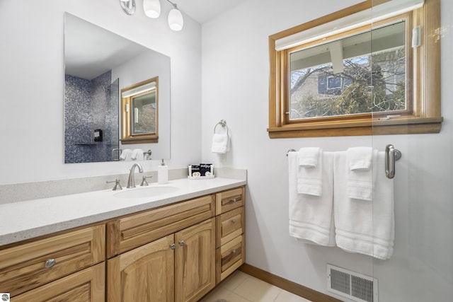 bathroom featuring vanity, baseboards, visible vents, walk in shower, and tile patterned floors