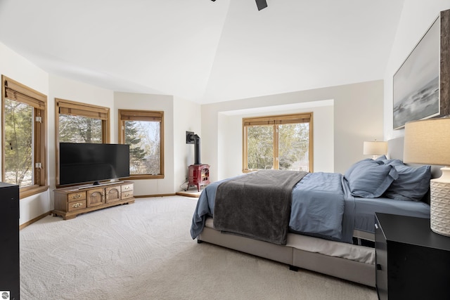 carpeted bedroom with baseboards, high vaulted ceiling, ceiling fan, and a wood stove