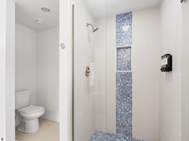 full bath featuring tile patterned floors, toilet, tiled shower, and baseboards