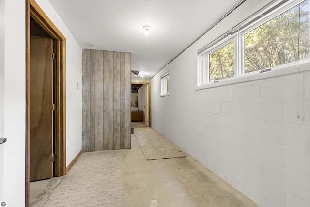 hall with unfinished concrete flooring and concrete block wall