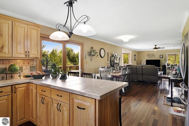 kitchen with tasteful backsplash, a peninsula, crown molding, tile counters, and dark wood-style flooring