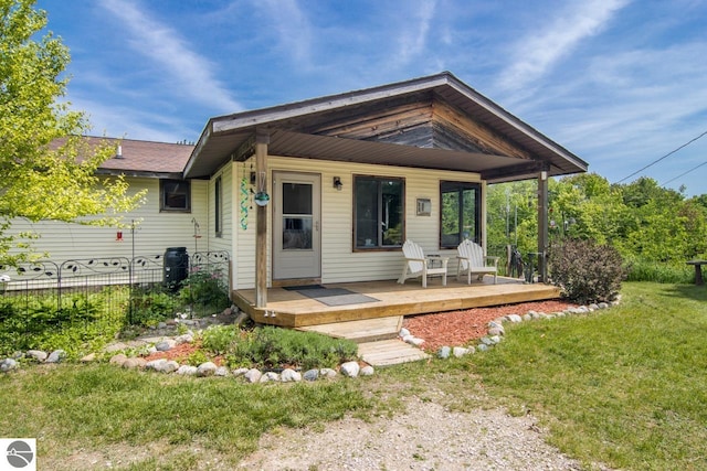 view of front facade with a deck, a front lawn, and fence